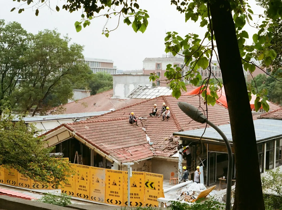 Flat Roof Repair in Lawndale — roofers replacing a red tile roof behind a safety barrier